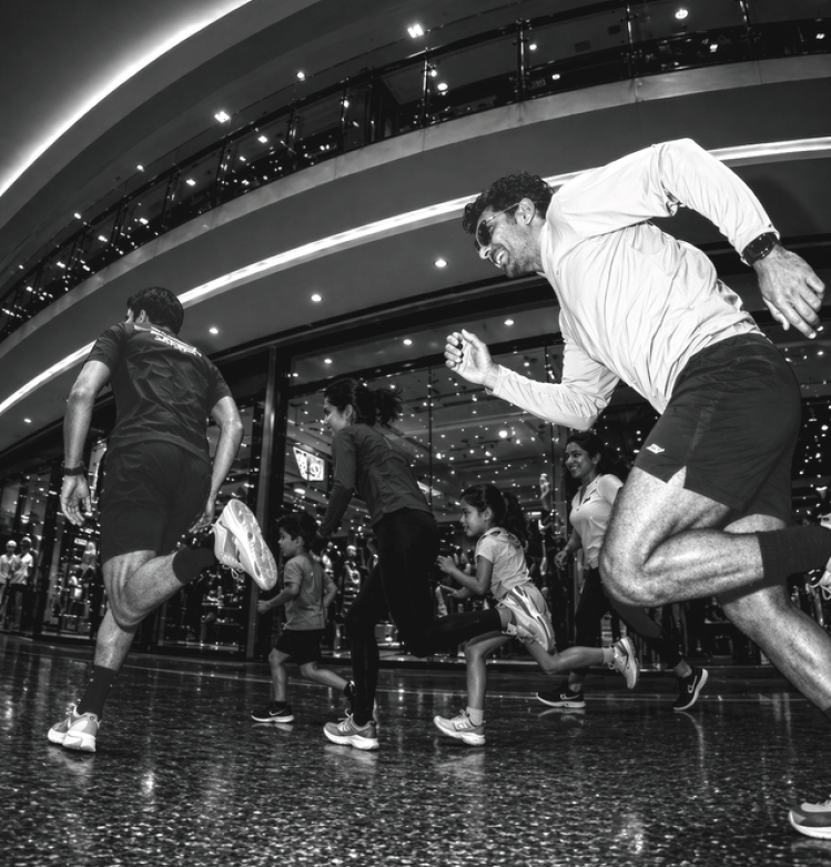 A large, diverse crowd walking through a brightly lit modern indoor walkway during a community event.